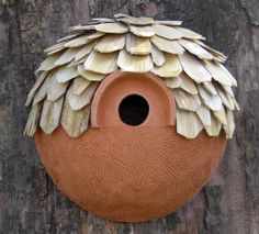 a clay birdhouse with feathers on it's roof