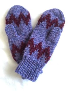 two knit mittens sitting on top of a white surface