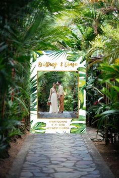 a couple standing in the middle of a walkway surrounded by greenery