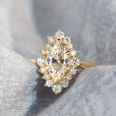 a yellow gold ring with an oval cut diamond surrounded by smaller round diamonds on top