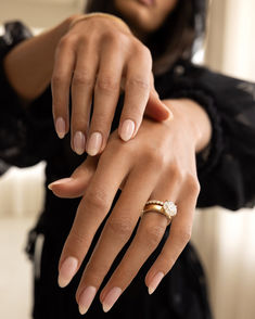 a woman holding onto her wedding ring with one hand and the other on her arm