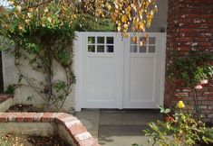 a white door is open in front of a brick wall and shrubbery with yellow flowers