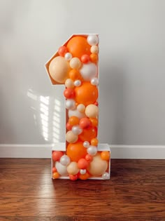 an orange and white number one made out of balloons on top of a wooden floor