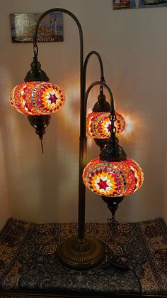 three lamps are lit up on top of a carpeted area in front of a wall