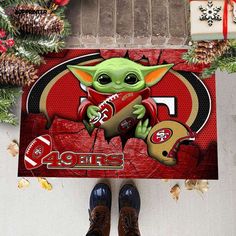 the baby yoda is holding a football in his hand and standing next to a christmas wreath