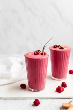 two glasses filled with raspberry smoothie on a cutting board