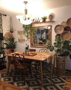 a dining room table and chairs in front of a mirror with plants on the wall