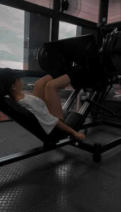 a woman laying on top of a bench in a gym