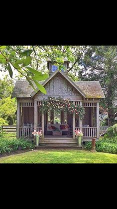 a wooden gazebo with flowers on it in the middle of some grass and trees