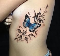 a woman's stomach with a butterfly and flowers tattoo on the side of her body