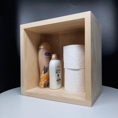 two rolls of toilet paper are in a wooden box next to some other bathroom products