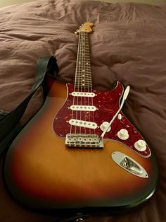 an electric guitar laying on top of a bed