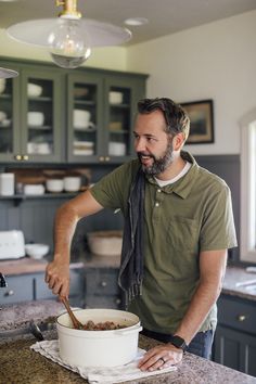 a man standing in front of a bowl of food on top of a kitchen counter