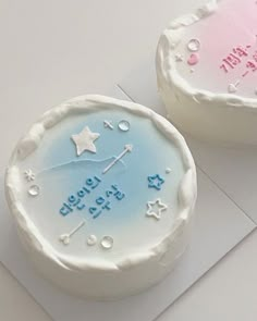 two cakes with frosting and stars on them sitting on top of a white table