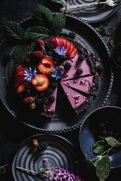 there is a cake with fruit on it and other desserts around the cake plate