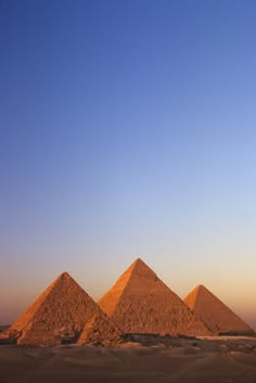 three pyramids in the desert at sunset