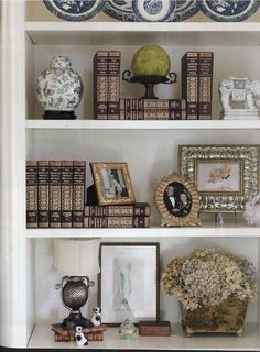 a white book shelf filled with books and vases