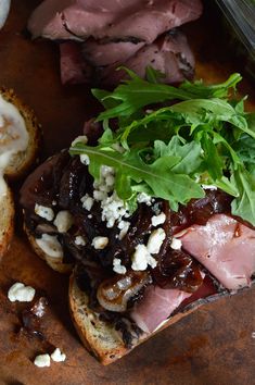 an open faced sandwich with meat, cheese and lettuce next to other food items