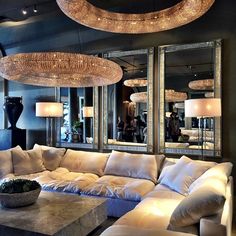 a living room filled with lots of furniture and mirrors on the wall next to it