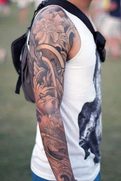 a man with a dragon tattoo on his arm and shoulder is standing in the grass