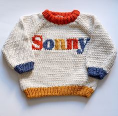 a knitted sweater with the word sorry written in red, white, and blue