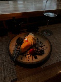 a plate that has some food on it next to a wine glass and spoons