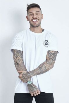 a man with tattoos standing in front of a white wall