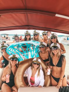 a group of women in bikinis posing for a photo on a boat at the beach