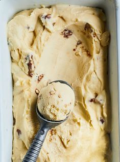 a scoop of ice cream in a white dish with a metal spoon on the side