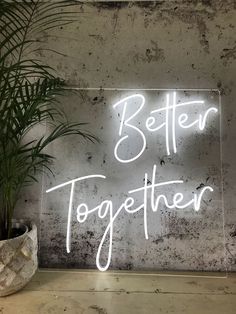 a neon sign with the words better together on it next to a potted plant