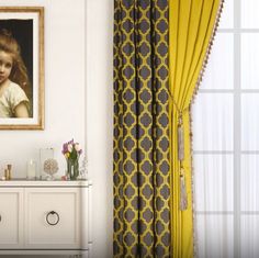 there is a painting on the wall next to a white dresser and yellow drapes