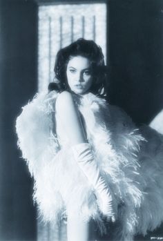 a black and white photo of a woman in a feathered coat with gloves on