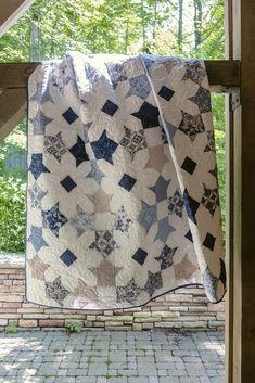 a blue and white quilt hanging on a window sill with trees in the background