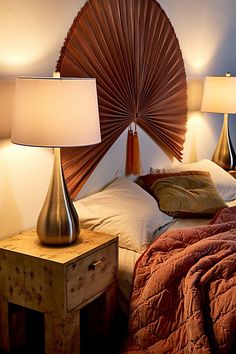 a bed with two lamps on either side of it and a fan shaped headboard