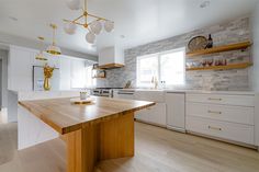 a kitchen with white cabinets and wooden counter tops, along with an island in the middle