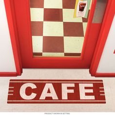 a red door with the word cafe painted on it in front of a checkered floor