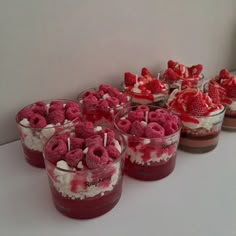 several desserts with strawberries and whipped cream in small glass dishes on a table