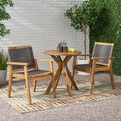 two chairs and a table sitting on top of a rug in front of a white brick wall