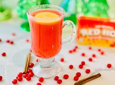 a glass mug filled with liquid next to cinnamon sticks and candy canes on a table