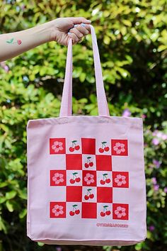 Pack up a picnic in this vibrant pink tote bag, displaying a checkerboard of cherries and cherry blossoms. **Care/Import** * Made of durable 15 oz pink cotton canvas. * Machine wash in cold, tumble dry on low, iron on low * Made in the USA **Dimensions** * 10" W x 14" H x 5" G | Overseasoned Cherry Picnic Tote Bag at Free People in Pink Retro Cotton Bags For Spring, Retro Pink Cotton Bag, Spring Picnic Cotton Bag, Summer Cotton Bag For Picnic, Cotton Summer Picnic Bag, Cotton Picnic Bag For Summer, Spring Square Canvas Shopping Bag, Pink Square Canvas Bag For Shopping, Red Spring Picnic Bag