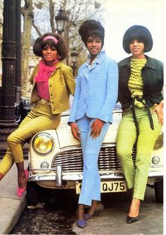 three women sitting on the hood of a car