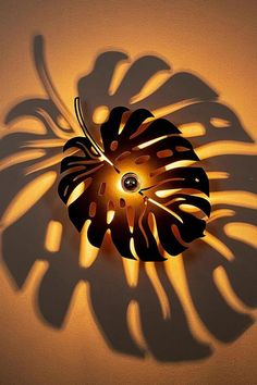 a light that is on the side of a wall with a plant shadow in it