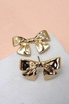 Classic Bow Ribbon Stud Earrings, a timeless adornment that effortlessly combines sophistication with a touch of whimsy. These earrings feature a delicately designed bow ribbon, adding a classic and versatile charm to your ensemble. Product Details:Width: 1" Length: .75"Earring back: PostMetal finish: gold, rhodium PlatedProduct: Lead & Nickel CompliantAnti-tarnish: Double E-coating Gold Earrings With Decorative Bow For Formal Occasions, Elegant Gold Earrings With Bow Tie Detail, Formal Gold Earrings With Decorative Bow, Elegant Ribbon Earrings For Wedding, Elegant Rose Gold Earrings With Bow, Gold Wedding Jewelry With Butterfly Knot Detail, Elegant Rose Gold Bow Earrings, Elegant Wedding Earrings With Ribbon, Classic Bow Earrings For Anniversary