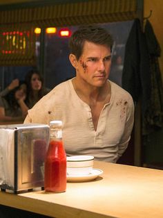 a man sitting at a table in front of a toaster with ketchup on it