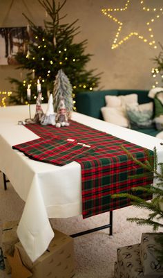 the table is set up for christmas with presents on it and trees in the background