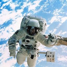 an astronaut floating in the air with his arms out and one hand raised up above him