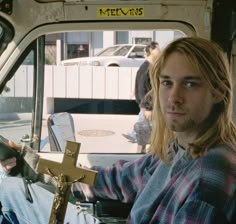 a man sitting in the back of a truck with a cross hanging from it's side