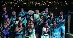 a group of people dressed in costumes posing for a photo with their hands up to the sky