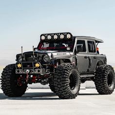 a large gray truck with four wheels and lights on it's flatbed in the desert