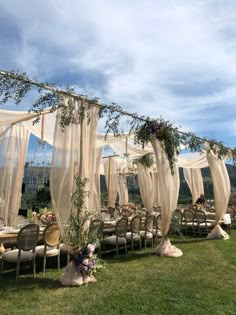 an outdoor wedding setup with sheer curtains and flowers